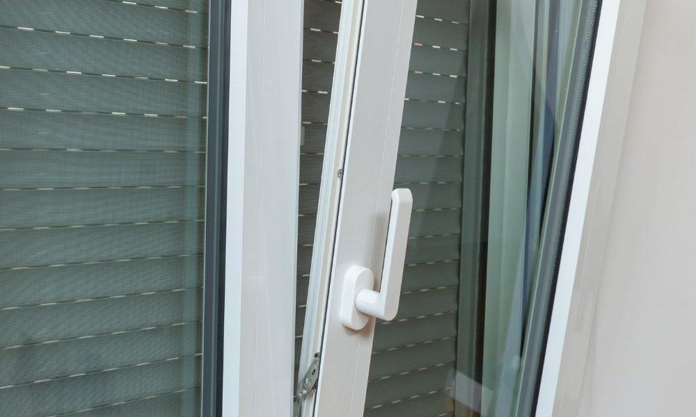 Ventana de aluminio de color blanca abierta con las persianas bajadas